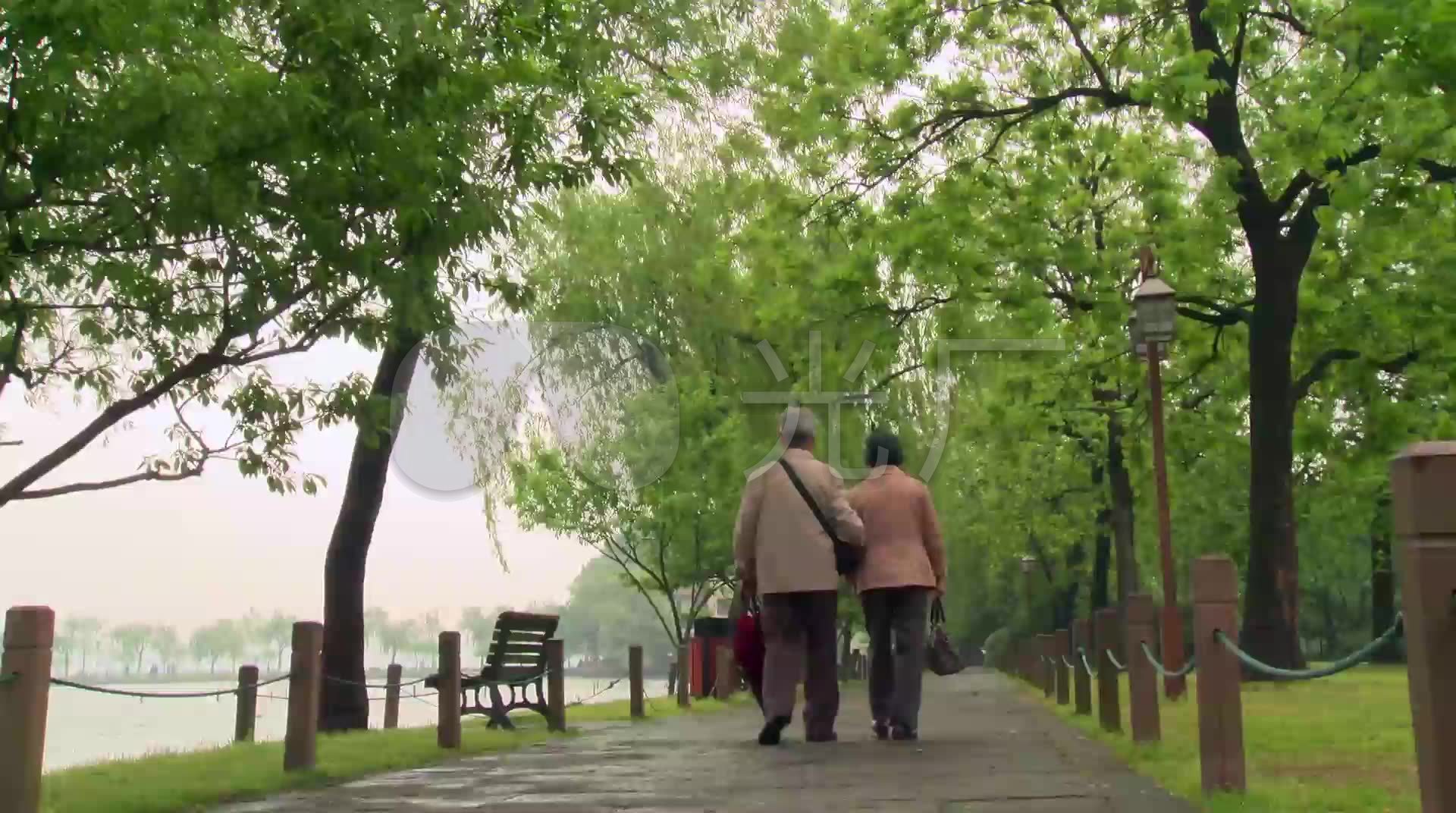 雨中同一把伞雨后相互挽扶着的老夫妻背影