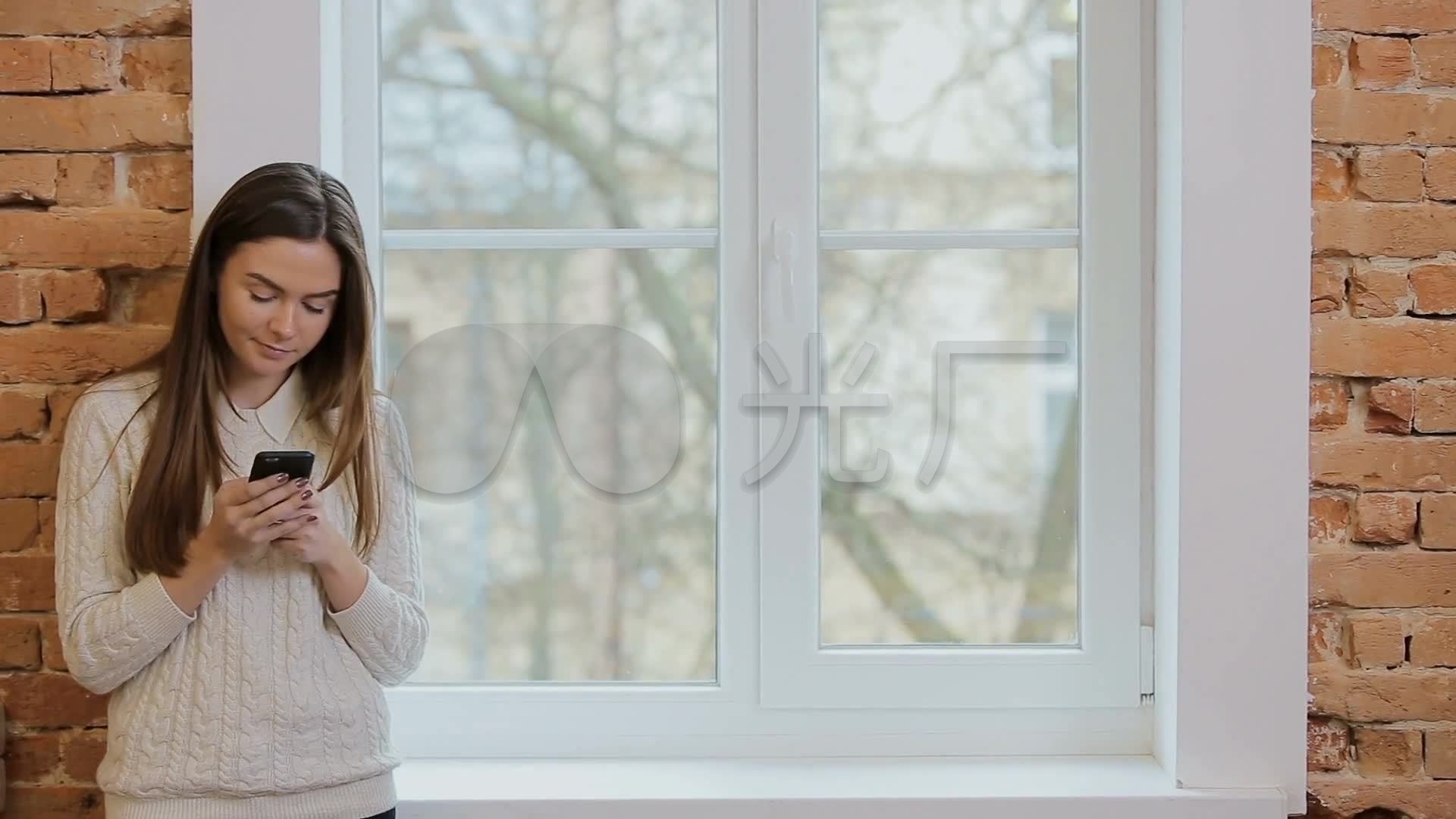 工作闲暇时间站在窗边玩手机的女人