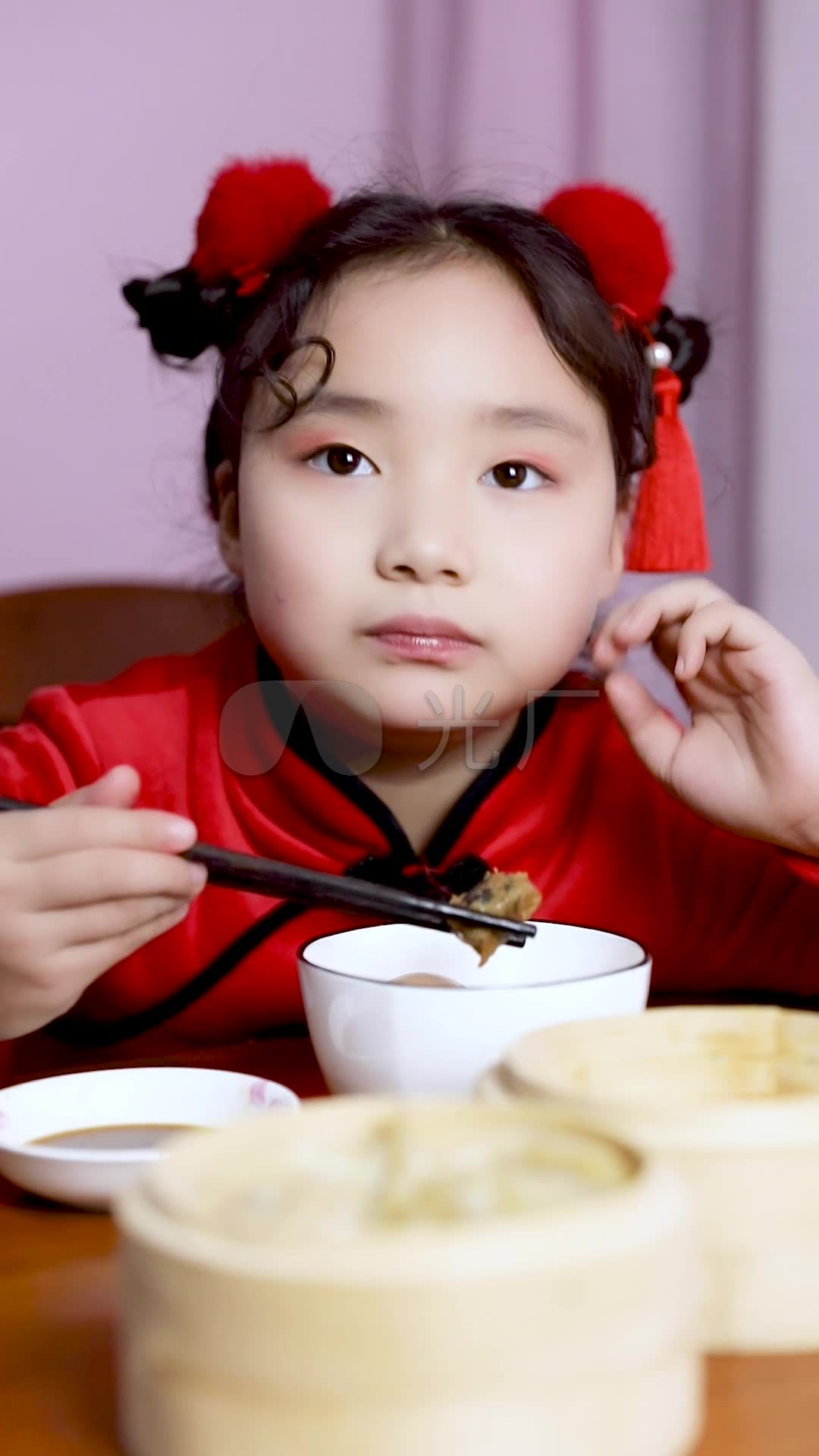 可爱的中国小女孩穿着新年服装吃饺子