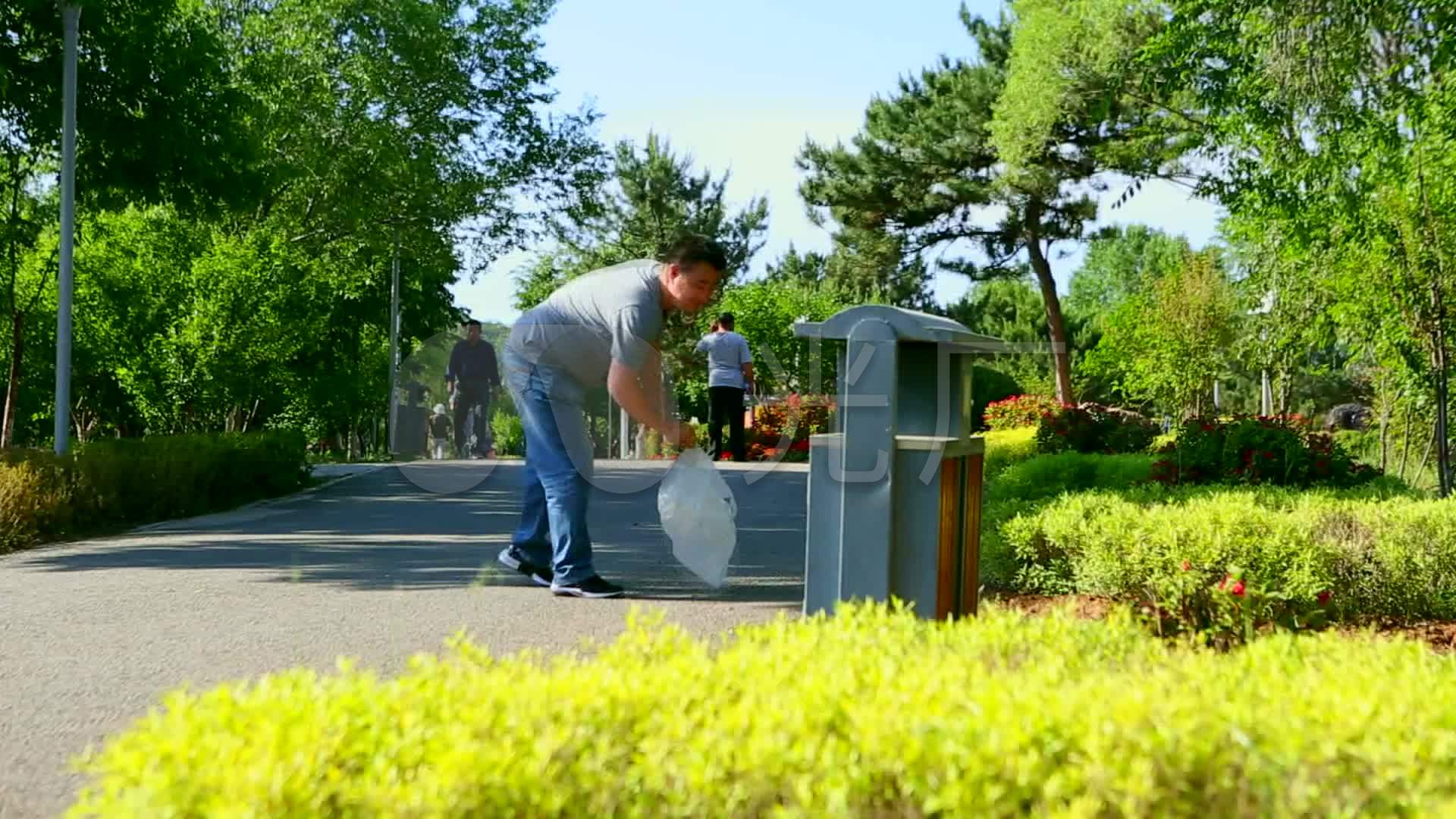 文明行为行人在公园里捡垃圾扔到垃圾箱