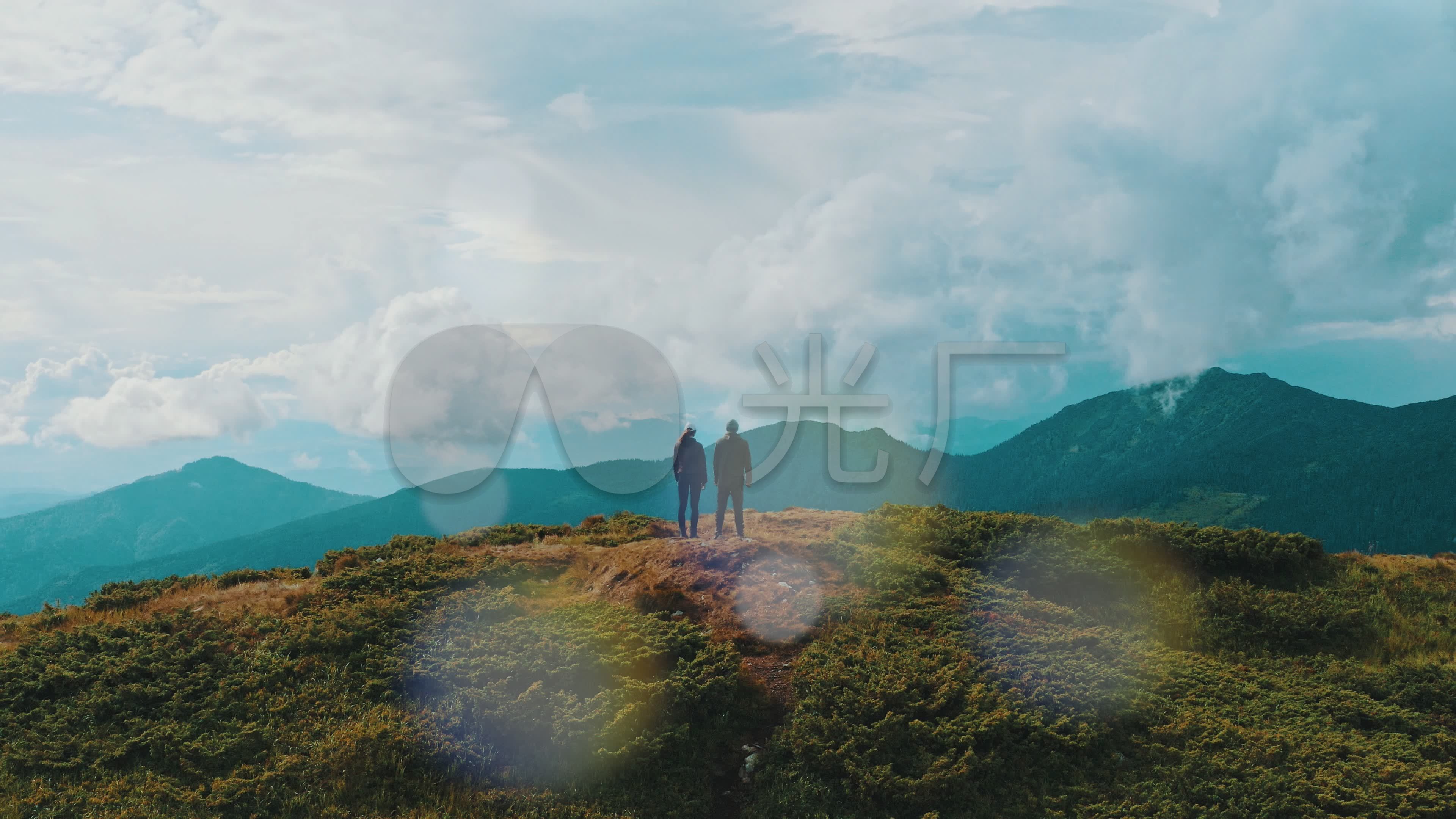 年轻的男女站在山顶上看风景