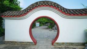 穿过中式园林庭院围墙圆形月亮门洞视频素材