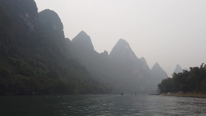 行驶中的竹筏船只阴雨绵绵河流青山绿水