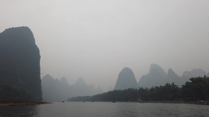 行驶中的竹筏船只阴雨绵绵河流青山绿水