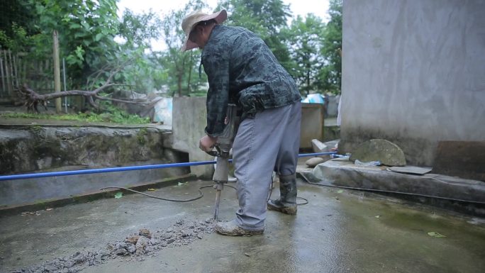 农村农民雨中工作电锤钻地