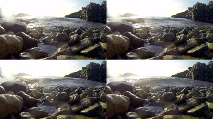 广角低角度拍摄海岸边鹅卵石海水扑面而来