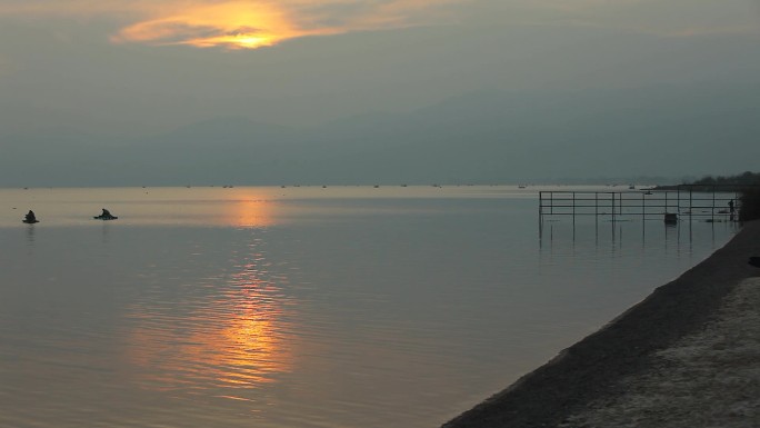 太阳落山前一瞬间，湖里的垂钓者