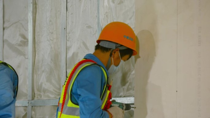 新型冠状病毒肺炎期间，工人戴口罩安装隔墙