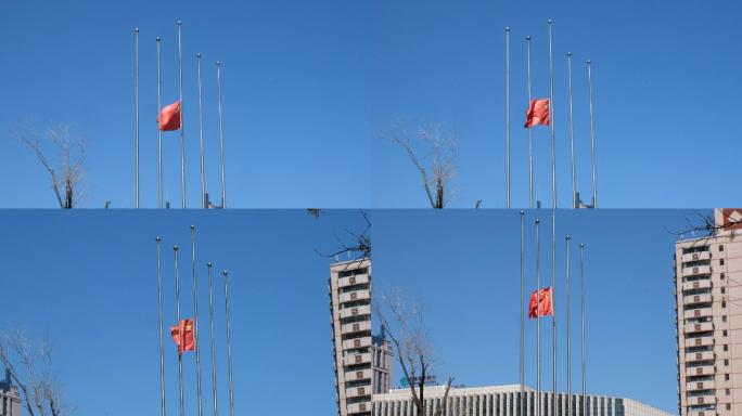 蓝天背景下降半旗的旗杆和飘扬的红旗