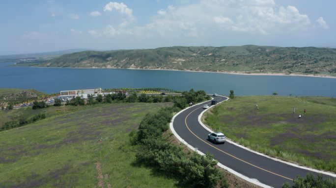 航拍白色汽车环湖公路行驶