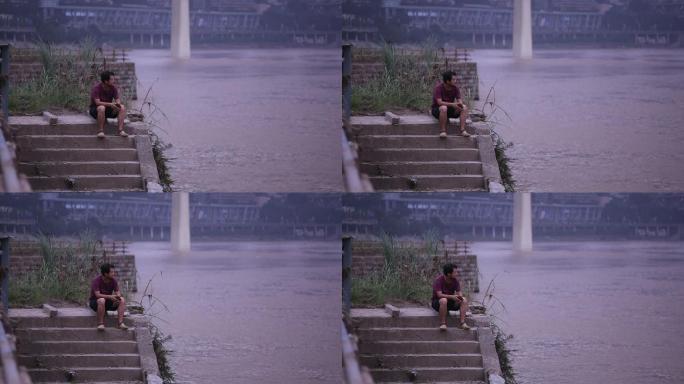 坐在嘉陵江边看着洪水发愁的男子