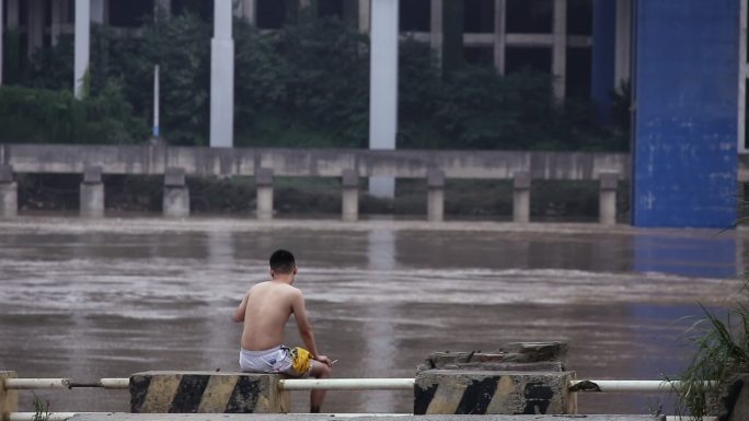 独自坐在嘉陵江边几乎被淹没的公路赤膊男子