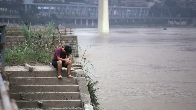 独自坐在重庆嘉陵江边抽烟的男子