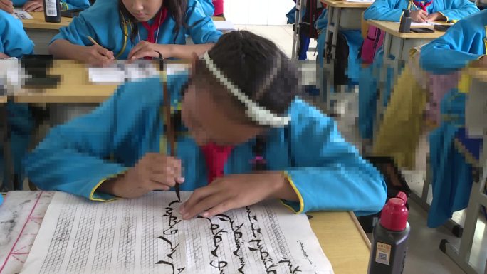 蒙古族学生身穿民族服装上蒙古文书法课