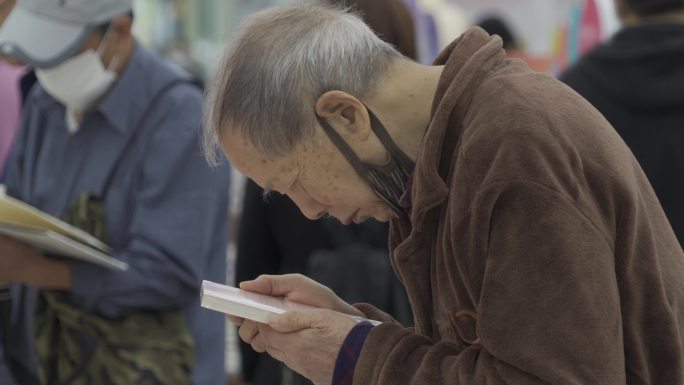 书展老人看书买书书籍全民阅读市民看书