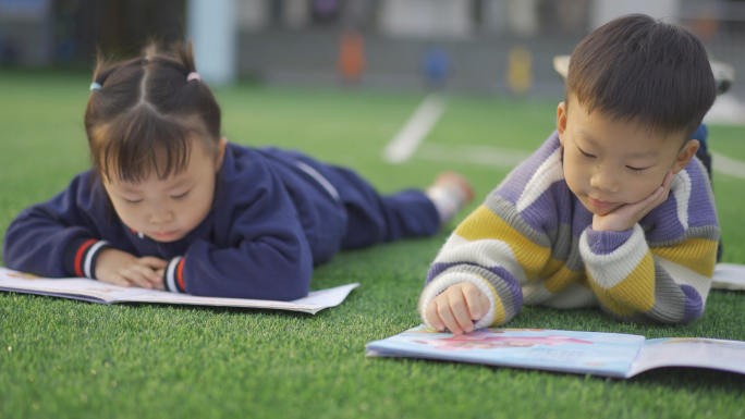 小孩子玩耍草地上看书