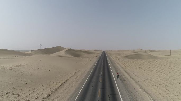 一个人行走在沙漠公路上