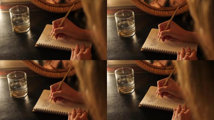 女孩在笔记本上书写文字，桌子上有一杯水