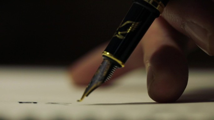 手拿钢笔在白纸上写字局部特写