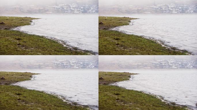 水库边水浪拍打岸边远处村庄