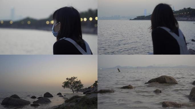 女孩戴着口罩在海边静心思考