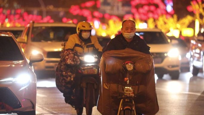 城市夜晚各种各样骑电动车的行人