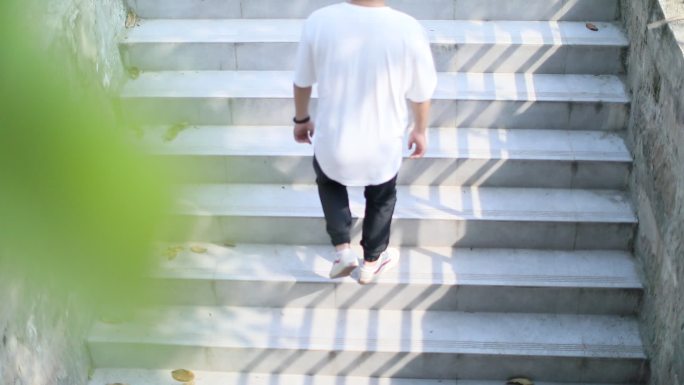 短袖T恤男子走上光影下的台阶