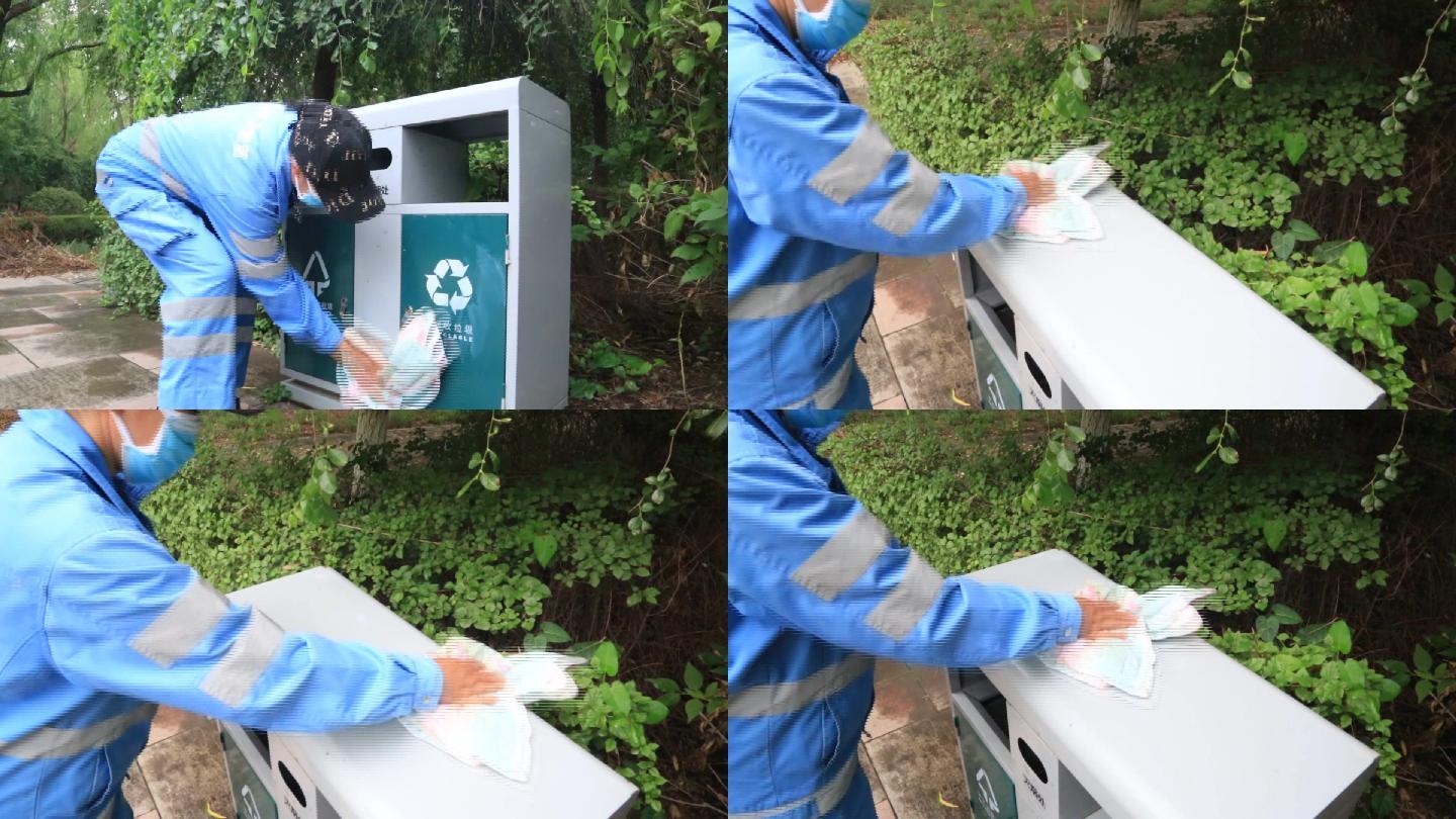 环卫工人用抹布清洁马路边的垃圾桶