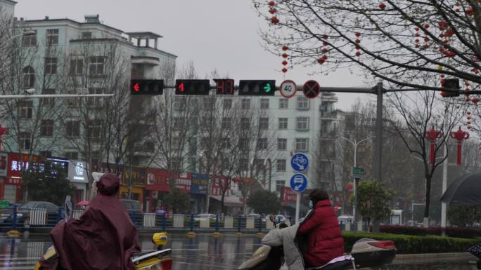 下雨天行人穿雨衣骑电动车红绿灯