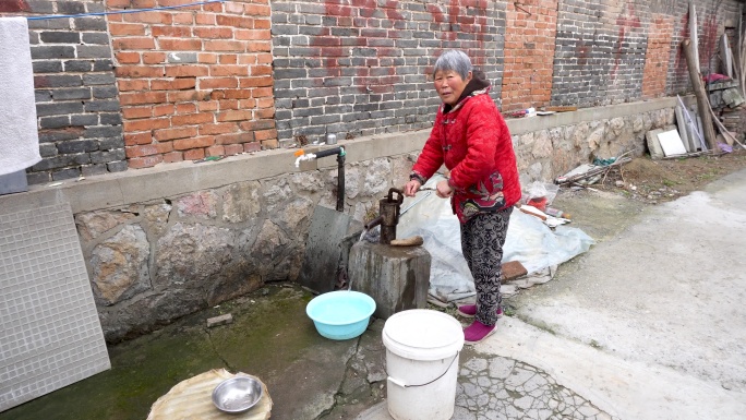 农村老人使用压水井打水