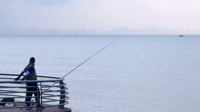 清晨海边钓鱼爱好者海钓鱼竿