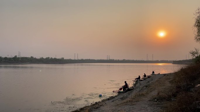 黄昏下河水边钓鱼的人群