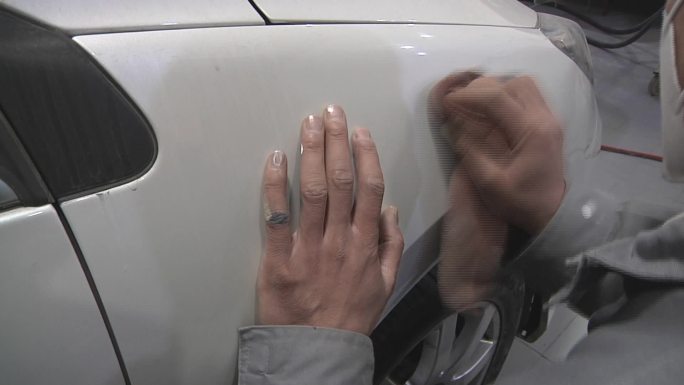 汽车钣金工维修工擦拭喷完漆的汽车