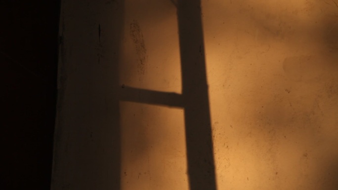 夕阳下的梯子影子映在墙上