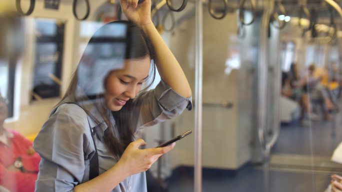 在地铁里用智能手机的年轻女子