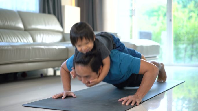 在家里背着宝宝做俯卧撑的男人。