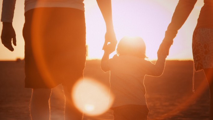 海滩上的家人夕阳下的一家三口剪影走向夕阳