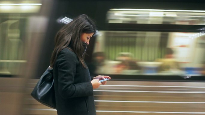 在地铁站使用智能手机的年轻女子。
