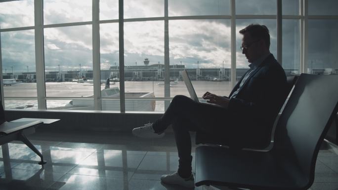 在机场候机时使用笔记本电脑的企业家