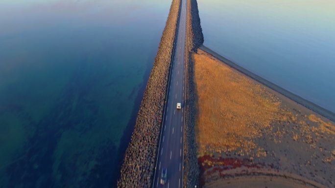 远景：鸟瞰汽车沿着公路行驶在遥远的山湖上