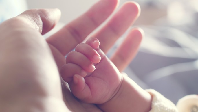 牵着新生婴儿的手呵护珍爱幼嫩