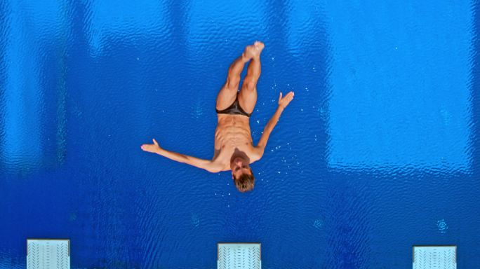 男子运动员跳入游泳池时在空中做旋转动作
