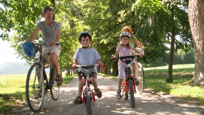 一家人带着两个孩子在公园里骑车