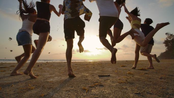 一群朋友日落时在沙滩上奔跑