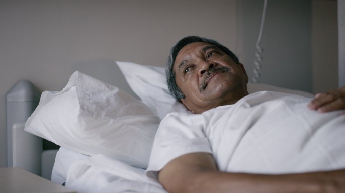 一名老年病人躺在医院病房的床上