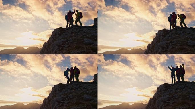 日落时分，三个登山者在山顶击掌