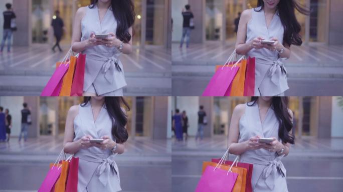 年轻女子提着购物袋用智能手机发短信