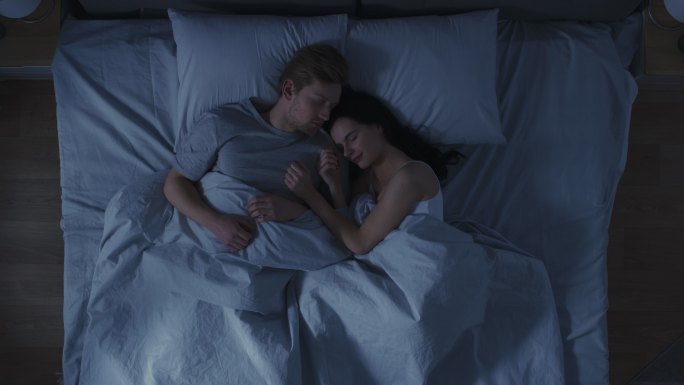 年轻夫妇在床上依偎着睡觉