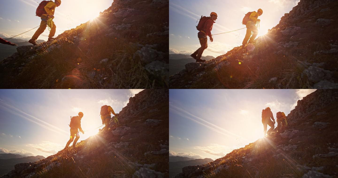 两个登山者在夕阳下爬山