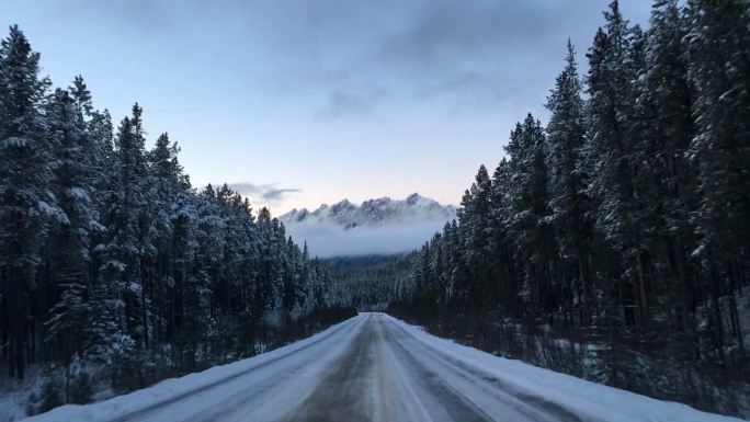 开车穿过国家公园远处的雪山公路自驾雪天开